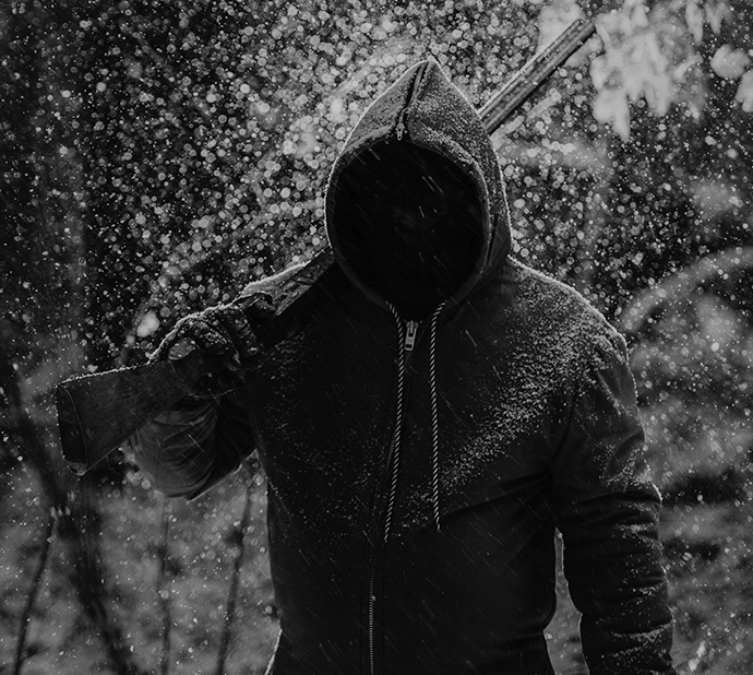 Cazador encapuchado con rifle en la nieve